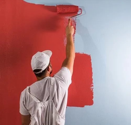 Painter applying fresh red paint to an interior wall