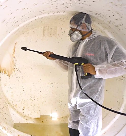 Technician pressure-washing the inside of a residential water tank in Dubai